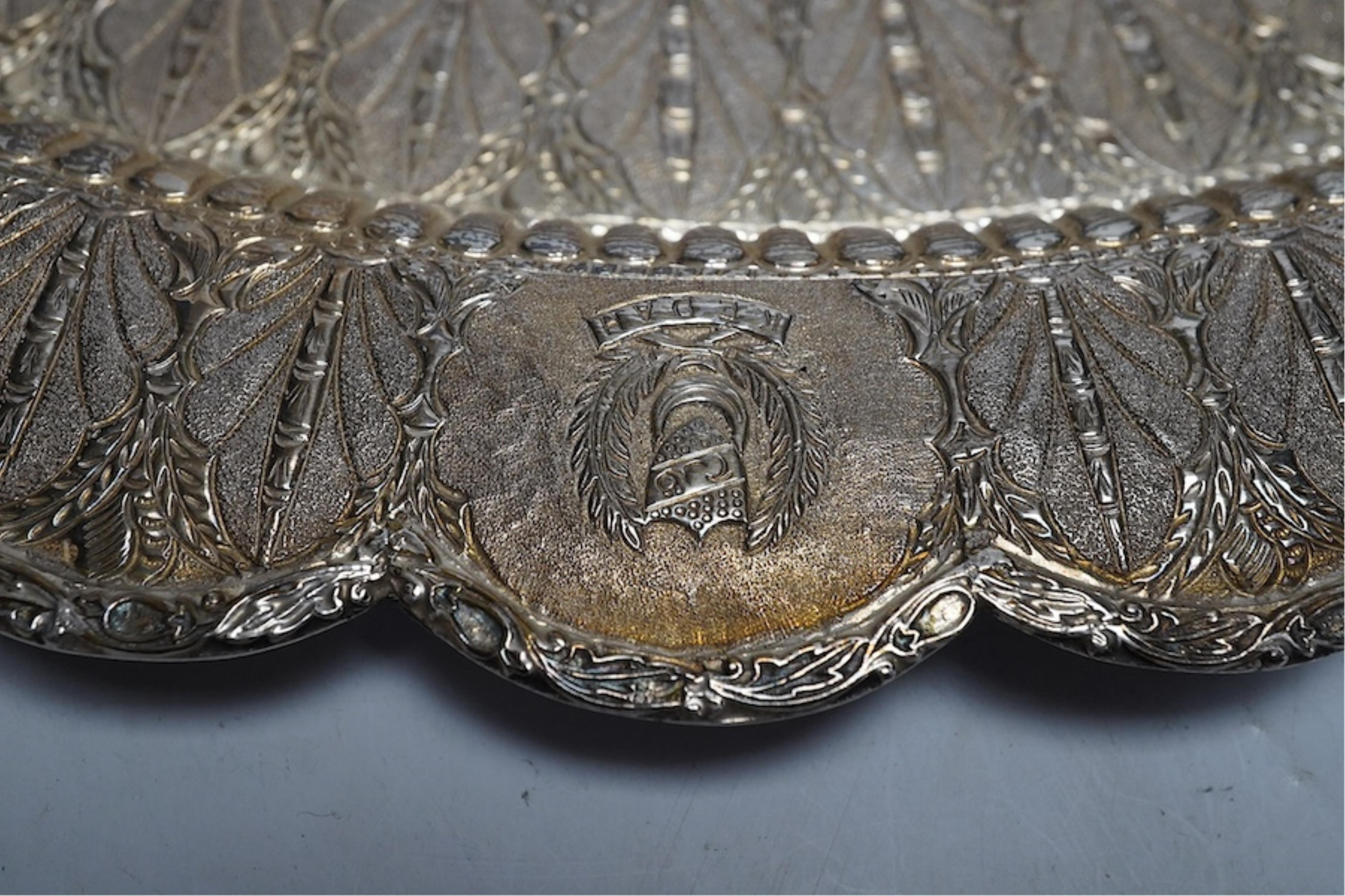 An Indonesian white metal oval dish, embossed and chased with the coats of arms of regions of Indonesia and Singapore, with a central leaf border and inscription, 38.5cm wide, 648g. Condition - good